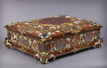 A colourful casket decorated with semi-precious stones, including jasper, agate, lapis lazuli and moss agate. The stones are held in gilt-brass mounts, which are engraved to resemble leaves. 