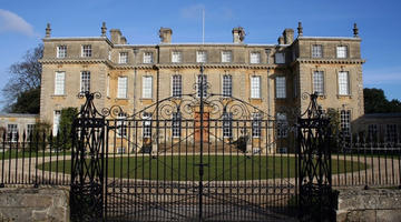 The facade of the mansion behind the locked iron gates