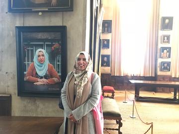 We are Bess at Hardwick Hall. Akeela Ahmed in front of her own portrait © National Trust - Gavin Repton, portraits by Rachel Adams, 2018
