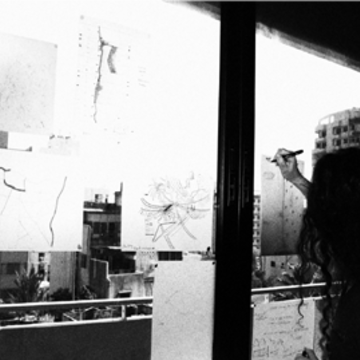 Image of a workshop participant drawing scores of the city through a window onto transparent paper during a workshop in Beirut.