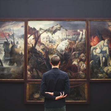 Person standing facing a large painting