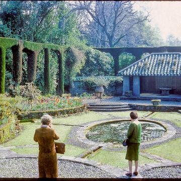 A slightly saturated picture of the Mount Stewart garden with two women admiring the landscape. They have their backs turned to the camera.  