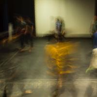 Actors rehearsing in a theatre, rays of light blur across the photo and make the people blurry